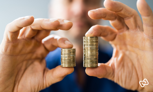 Eine Person hält zwei unterschiedlich hohe Münzstapel. Sie veranschaulichen Gehaltsunterschiede, die durch die EU-Entgelttransparenzrichtlinie sichtbarer werden sollen.