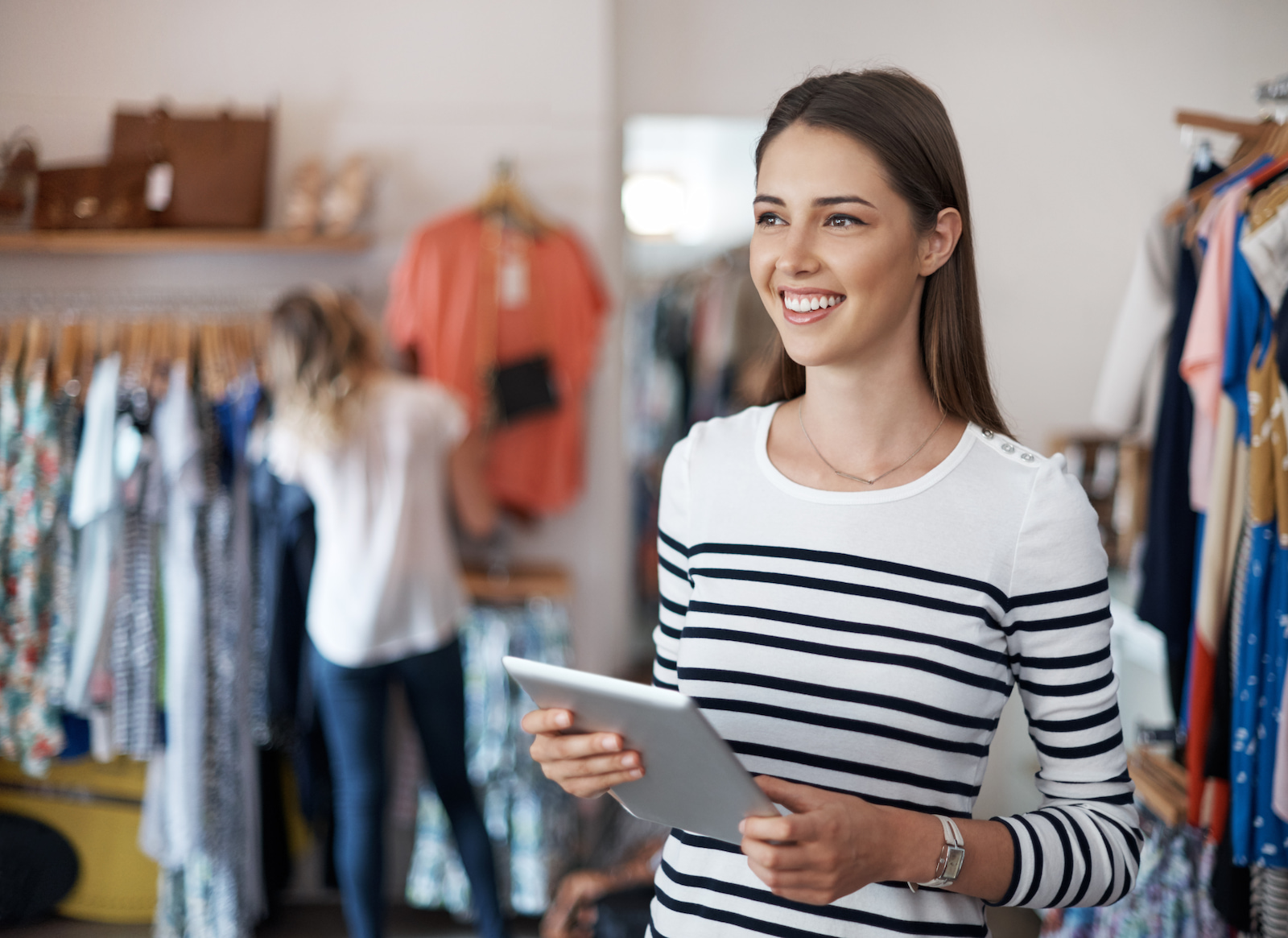 Eine selbstbewusste Filialleiterin in einem Bekleidungsgeschäft überprüft den Lagerbestand und arbeitet mit Mitarbeitenden zusammen, um den Betrieb zu optimieren.