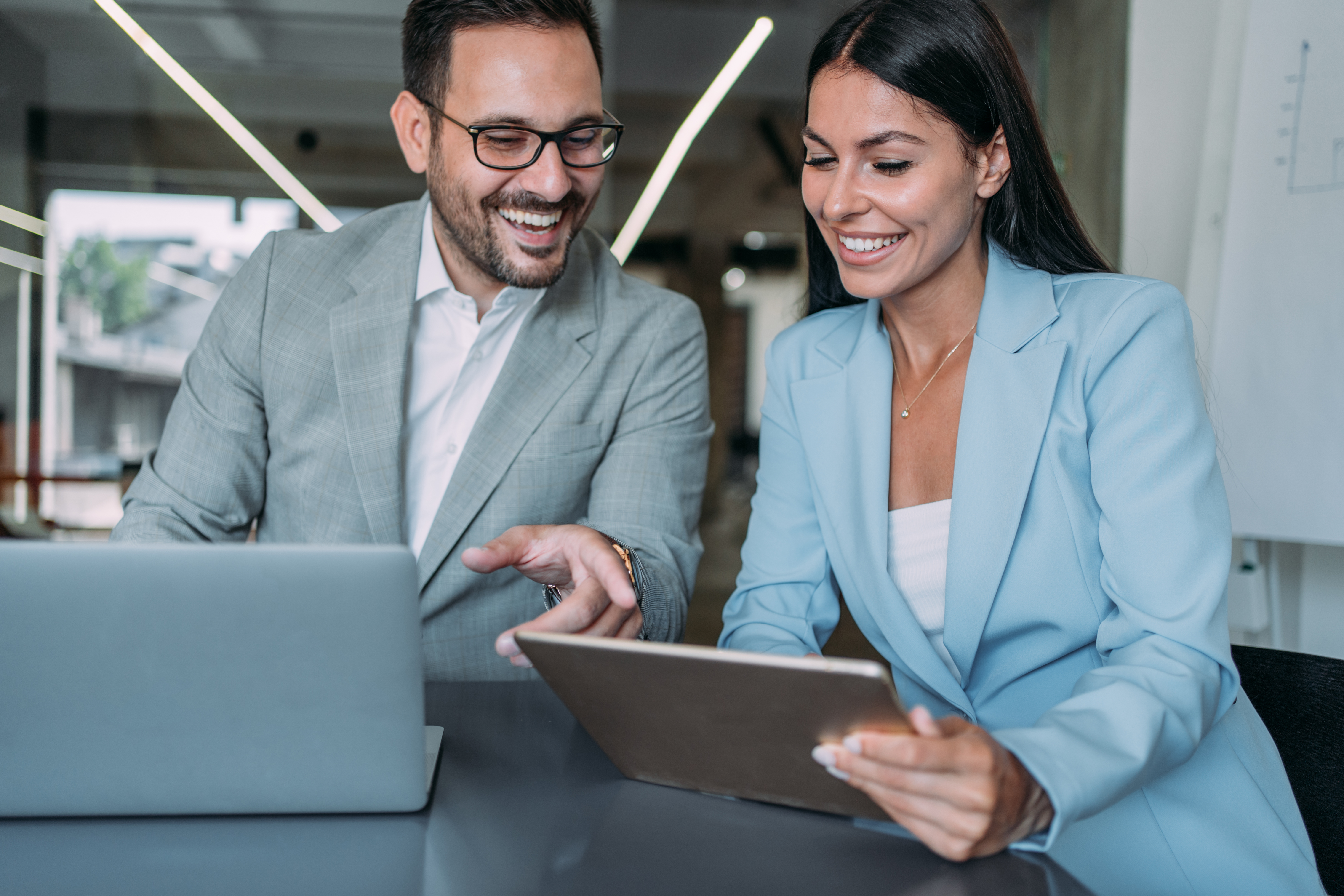 Frau und Mann arbeiten an einem Laptop im Büro an Entgelttransparenz und der Prüfung von Entgeltdaten.