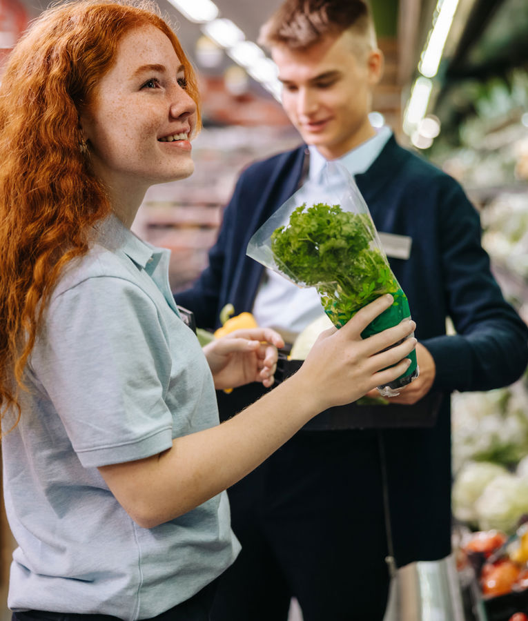 Eine freundliche Verkaufsmitarbeiterin hilft einem Kunden bei der Auswahl frischer Bio-Produkte und verbessert das Kundenerlebnis.