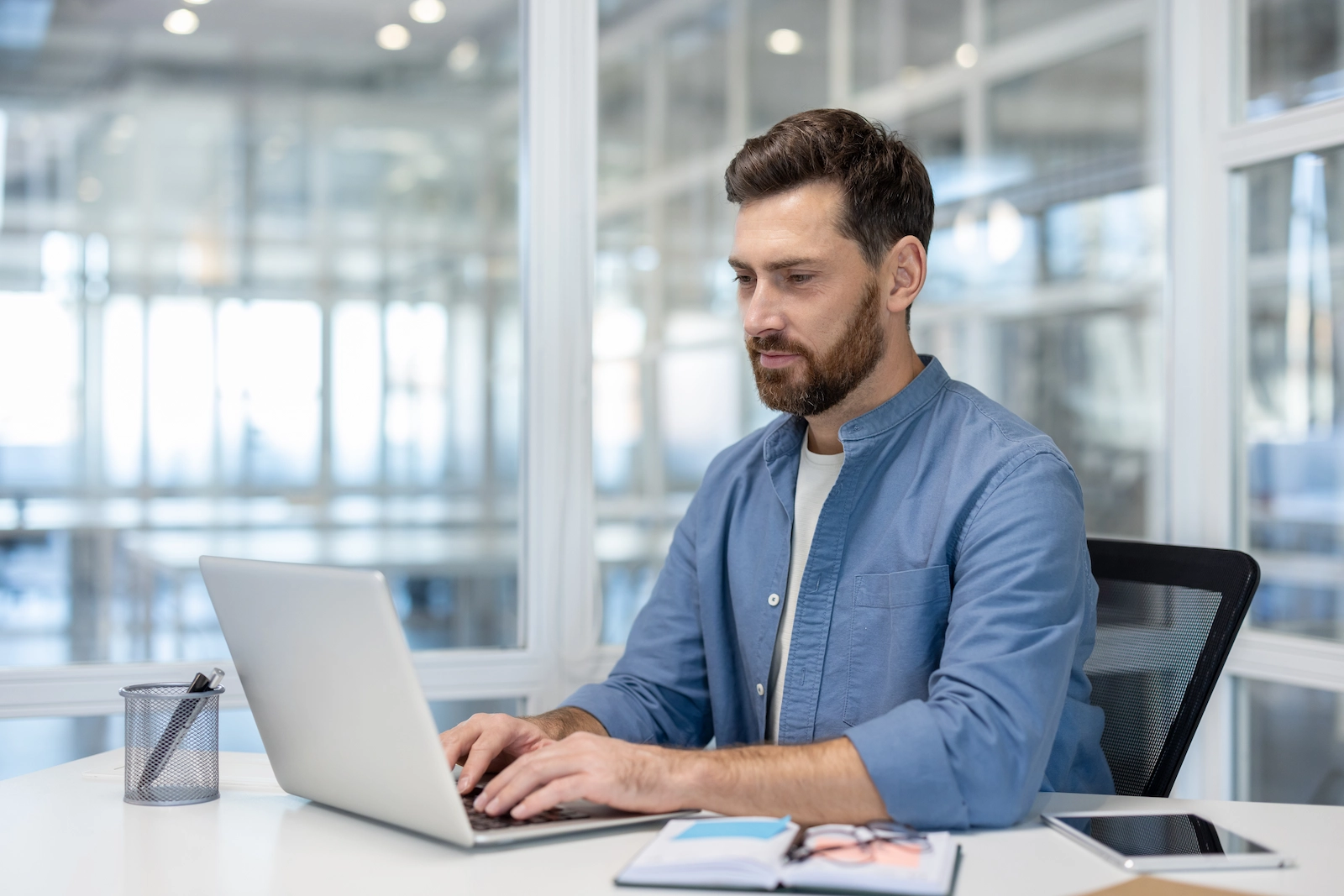 Büroangestellter arbeitet am Laptop in einem modernen Büro und nutzt digitale Workforce-Management-Tools für Einsatzplanung, Zeiterfassung und HR-Planung.