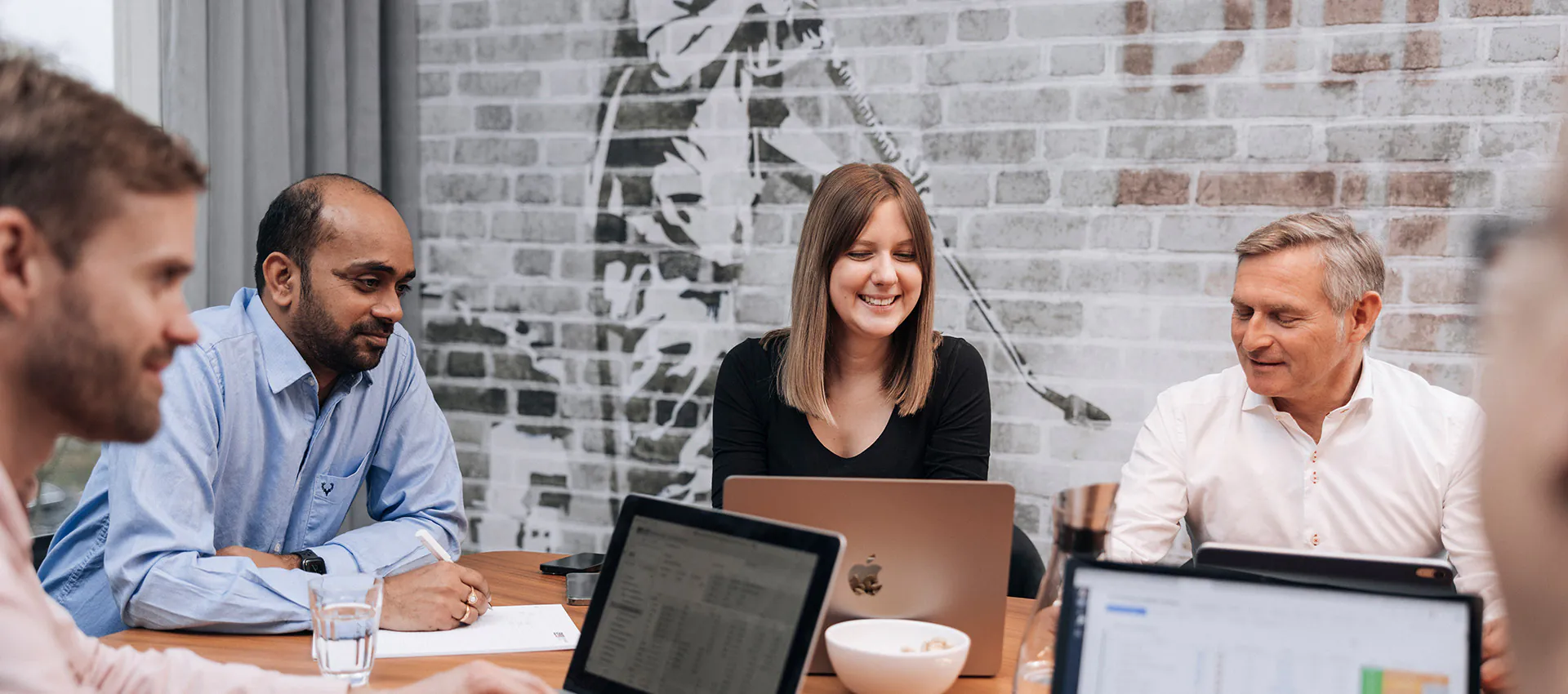 Mitarbeitende von Software4You arbeiten im Meeting gemeinsam an Laptops, analysieren HR-Daten und nutzen Planungs-Tools mit Timegrip-Integration zur Personaloptimierung.